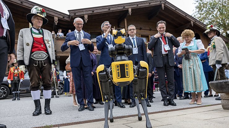 Tradizione e innovazione nel villaggio dei pensatori, il robot AI Spot consegna i badge agli ospiti d'onore: (da sinistra)  il capitano del Tirolo Anton Mattle, il presidente dell'Euregio e della Provincia di Bolzano Arno Kompatscher, il presidente della Provincia di Trento Maurizio Fugatti, il ministro federale austriaco Norbert Totschnig e la vicepresidente della Provincia di Bolzano Rosmarie Pamer. 