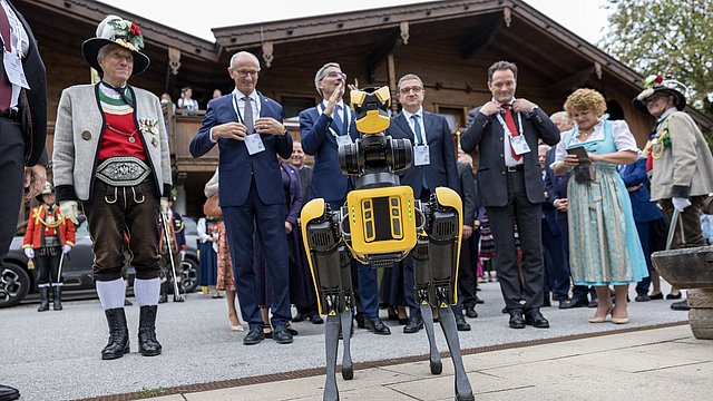 Tradizion y inuvazion tl luech de chiche pënsa: l robot AI Spot ti sëurandà I badges ai ghesć. Da man ciancia: reprejentanc dla Cumpania di Scizeri de Alpbach, LH dl Tirol Anton Mattle, l presidënt dl’Euregio y LH Arno Kompatscher, LH Maurizio Fugatti, l minister naziunel Norbert Totschnig y la vizepresidënta dla Provinzia de Bulsan Rosmarie Pamer.