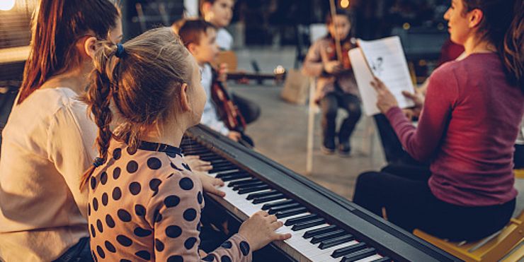 Gruppe von Kindern, die in der Musikschule Instrumente spielen lernen