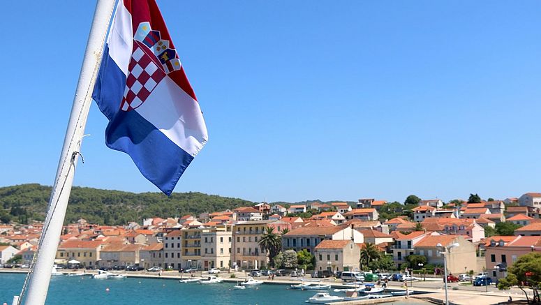 Bandiera croata sventola con una località di mare sullo sfondo.