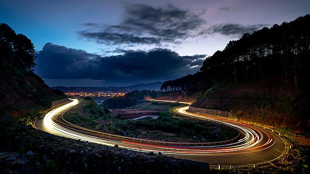 Fotografia a lunga esposizione di veicoli in movimento su strada curva.