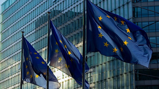 Tre bandiere dell’UE sventolano di fronte alle vetrate della Commissione europea di Bruxelles.